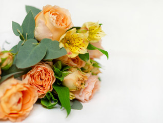 flower arrangement of orange roses and green leaves of eucalyptus in a vintage pot on a white...