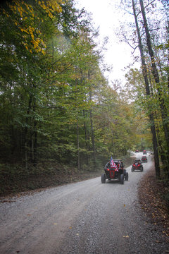 A string of buggies on dirt country road with the American Flag