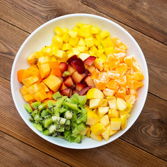 Fresh fruits salad glass bowl - mango, citrus, kiwi fruit, plum and persimmon. Healthy food. Square image.