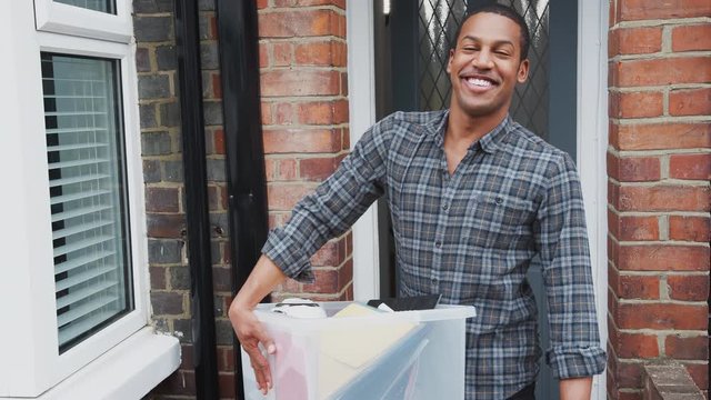 Portrait Of Male College Student Carrying Box Moving Into Accommodation