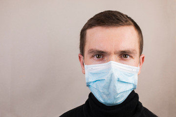 Guy in an antiviral mask, black turtleneck on a gray background