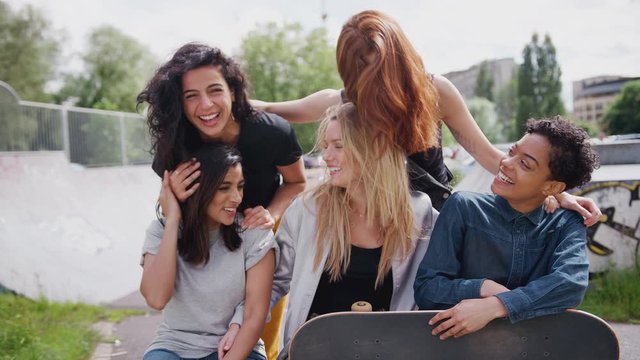 Portrait Of Female Friends With Skateboards Standing In Urban Skate Park