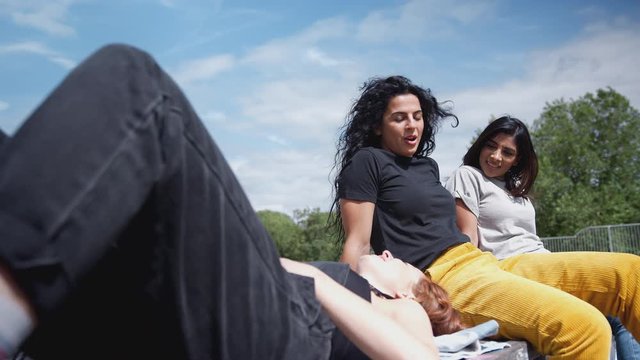 Three Female Friends Meeting And Relaxing In Urban Skate Park