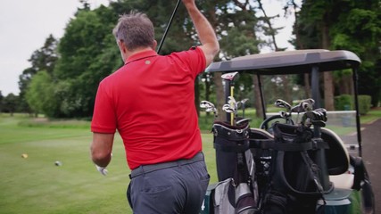 Mature Male Golfer Choosing Club From Bag On Buggy Before Placing Golf Ball On Tee 