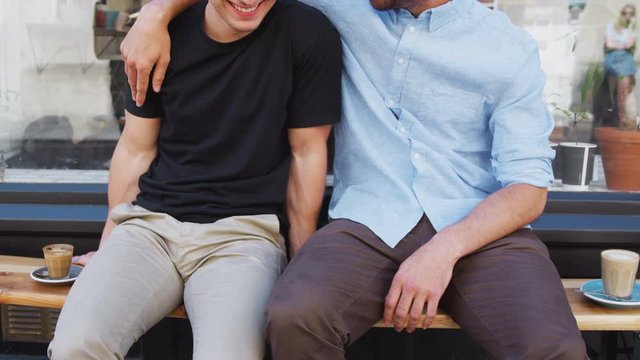 Close Up Of Loving Male Gay Couple Hugging Outside Coffee Shop