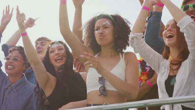 Group Of Young Friends Dancing Behind Barrier At Outdoor Music Festival 