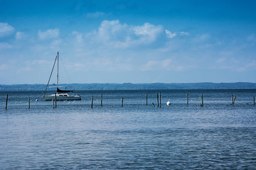 Sailboat on a lake next to wooden poles of a fish farm, vintage