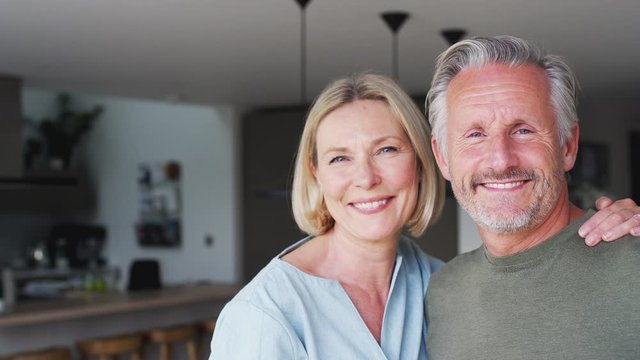 Portrait Of Smiling Senior Couple Standing In Kitchen Together