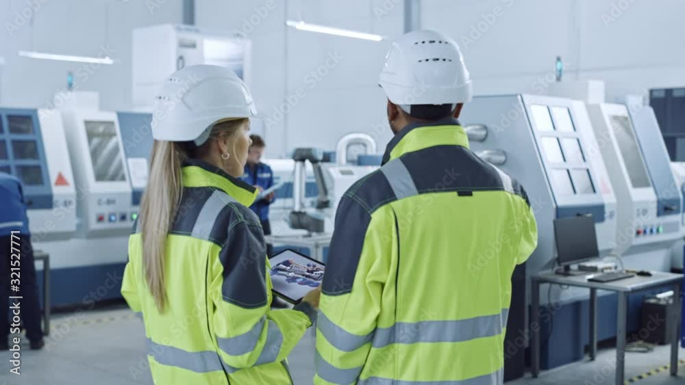 Aufkleber Industry 4.0 Factory: Chief Engineer and Project Supervisor in Safety Vests and Hard Hats, Talk, Use Digital Tablet Computer, Screen Shows 3D Concept of New Engine. Industrial Workshop with Machinery