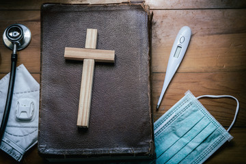 Cross with Holy Bible on wooden table, belief in treatment of God, Christian treatment concept.