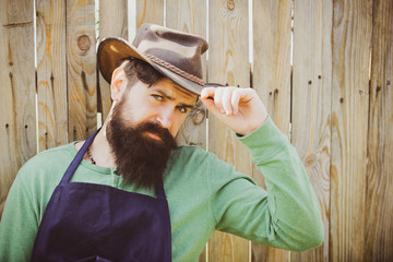 Portrait of bearded gardener on wooden background. Handsome man spend time in the farm. Worker...