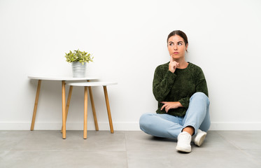 Young woman sitting on the floor thinking an idea