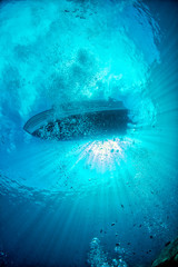 diving boat ship from underwater blue ocean with sun rays