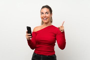 Young woman using mobile phone intending to realizes the solution while lifting a finger up