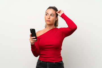 Young woman using mobile phone having doubts and with confuse face expression