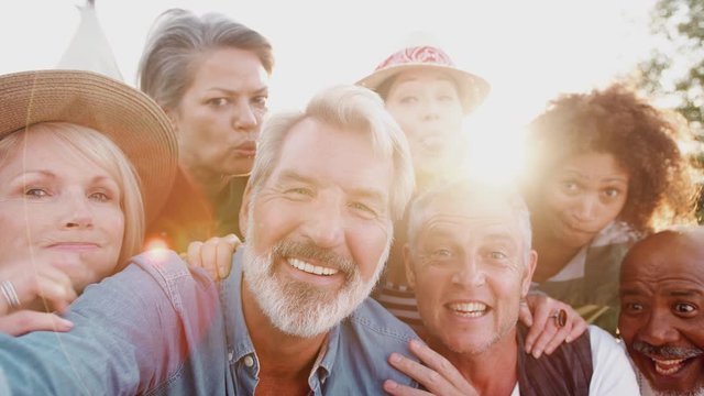 POV Shot Of Group Of Mature Friends Posing For Selfie At Outdoor Campsite