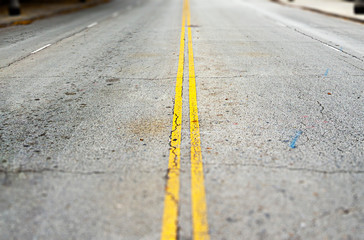 empty asphalt road with two continuous yellow lines painted on the surface.