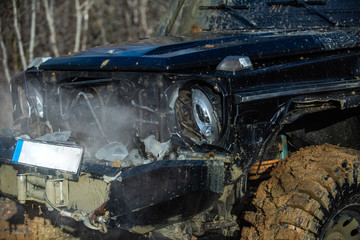 Travel concept with big 4x4 car. Beautiful nature. Offroad vehicle coming out of a mud hole hazard. Wheel in deep rut goes through mud and leaves trail. 4x4 Off-road suv car.
