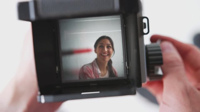 Photographer Looking Into Viewfinder Of Vintage Medium Format Camera Taking Portrait Of Young Woman