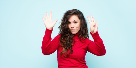 young pretty woman smiling and looking friendly, showing number nine or ninth with hand forward,...