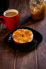 Bagel biscocho desayuno con mermelada de manzana y cafe en taza roja y cafetera italiana en mesa de madera