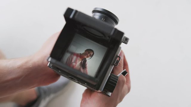 Photographer Looking Into Viewfinder Of Vintage Medium Format Camera Taking Portrait Of Young Woman
