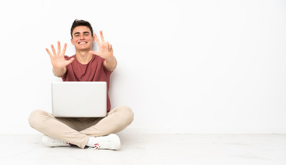 Teenager man sitting on the flor with his laptop counting eight with fingers