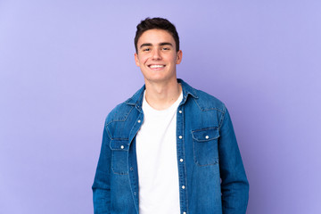 Teenager caucasian  handsome man isolated on purple background laughing