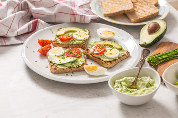 Fototapeta na wymiar Healthy breakfast from toasts with avocado spread guacamole egg tomato and chives.