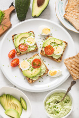 Healthy breakfast from toasts with avocado spread guacamole egg tomato and chives.
