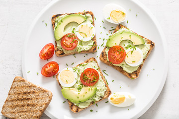 Healthy breakfast from toasts with avocado spread guacamole egg tomato and chives.