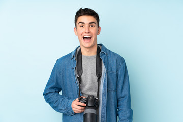 Teenager photographer man isolated on blue background with surprise facial expression