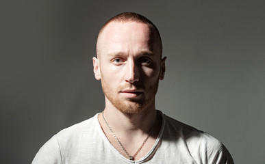 Ginger red bearded unshaven brutal man isolated at dark gray background studio photo. Handsome ginger man with beautiful blue eyes looking at camera. Unusual man appearance.