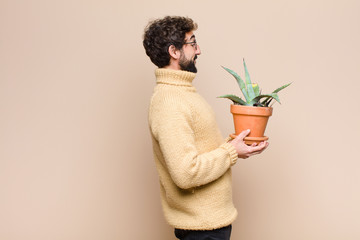 young cool man holding a cactus plant against flat wall