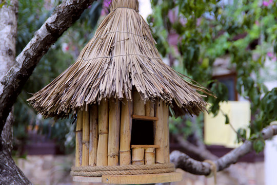 Image of a bird house. A bird house made of bamboo under a thatched roof. Handmade butterfly house. Close-up, horizontal, side view, free space, cropped shot.