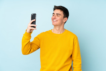 Teenager caucasian handsome man isolated on purple background making a selfie