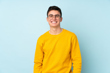 Teenager caucasian handsome man isolated on purple background with glasses and happy