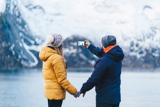 Tourist couple taking a smartphone picture at Hamnoy, Lofoten, Norway