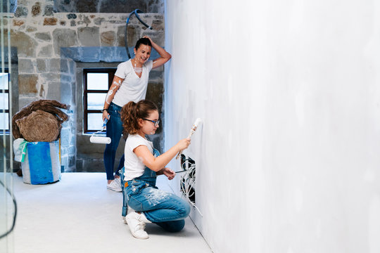 Mother and daughter painting a wall of her new house together