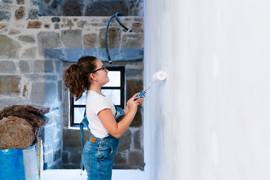 Girl painting a wall in a house