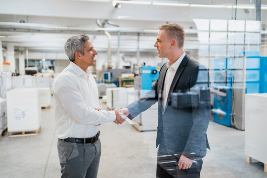 Two businessmen shaking hands in a factory