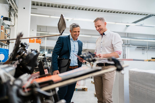 Two happy businessmen looking at folder in a factory