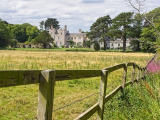 A view on the back side of Howth Castle near Dublin (Ireland) on an overcast summer day, with a meadow and a wooden fence in the foreground.