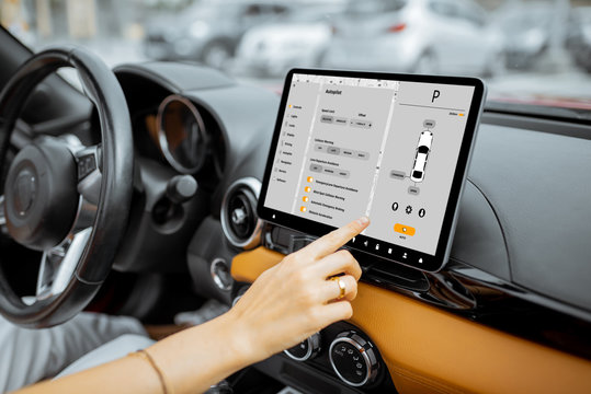 Woman controlling car with a digital dashboard switching autopilot mode, close-up on a touchscreen with launched program. Smart electric car concept
