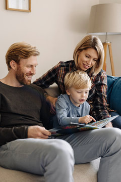 Family looking at book on couch at home