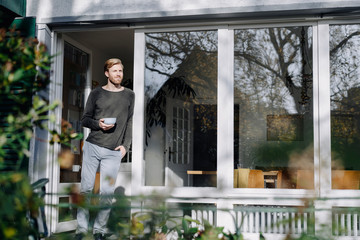 Man in sunroom at home leaning against the window