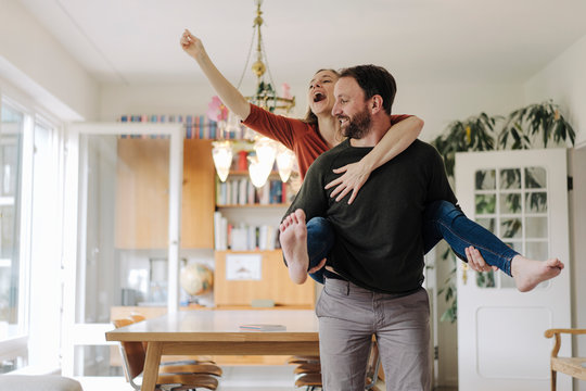 Man Carrying Happy Woman Piggyback In Their Comfortable Home