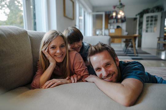 Happy family lying on couch, smiling at camera