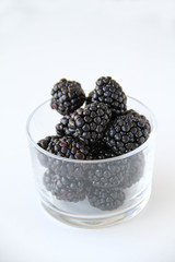 Fresh blackberries in a small glass on a white background. Healthy eating. Vegan food. Back view.