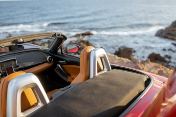 Convertible car on the rocky seaside, no people. Travel by car concept